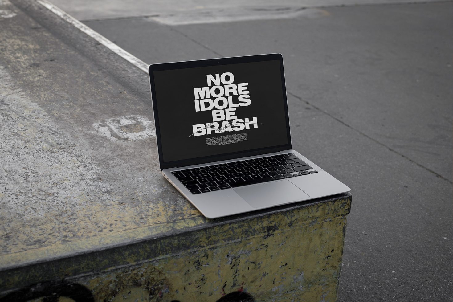 Laptop with a bold message on screen placed on urban street corner for mockup, showcasing modern font design and typography layout.